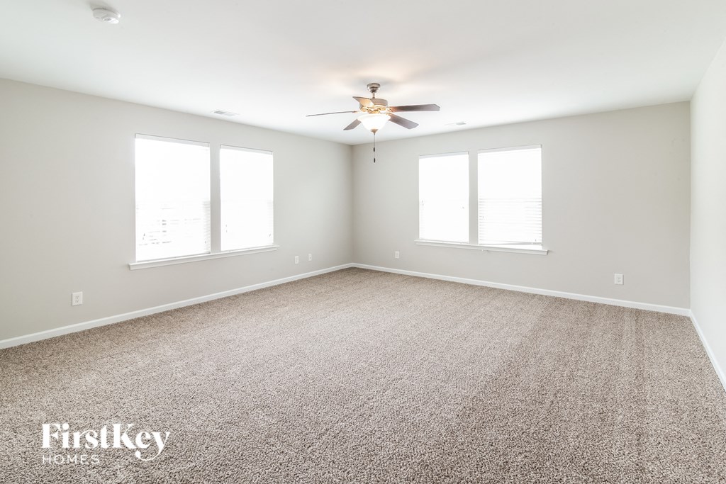a empty room with a ceiling fan and two windows
