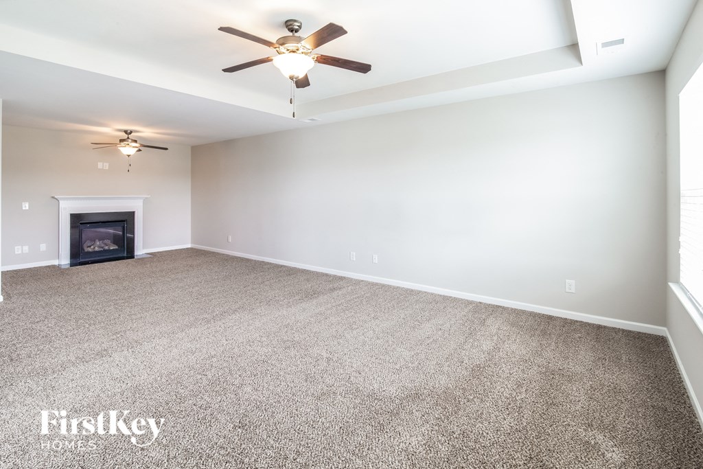 a empty living room with a ceiling fan and a fireplace