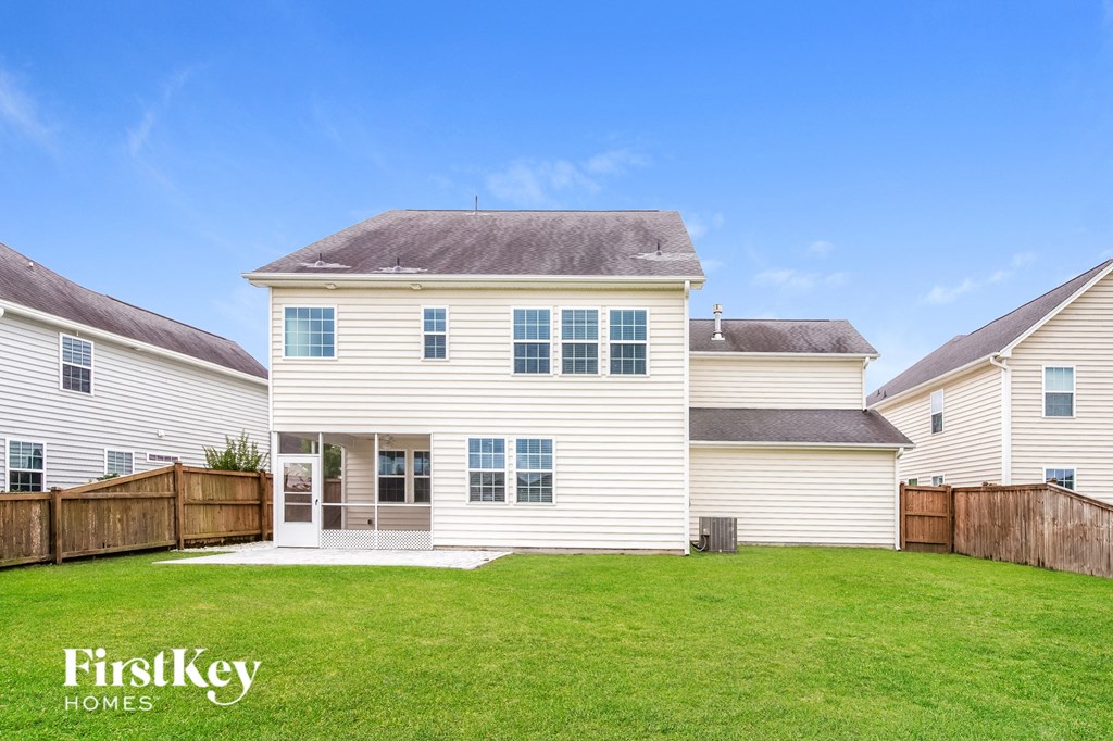 a white house with a green lawn and a wooden fence