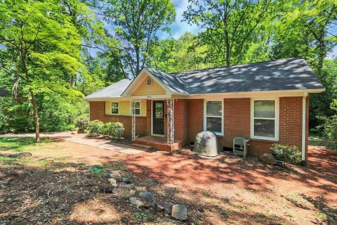 a small brick house with a tree in the yard