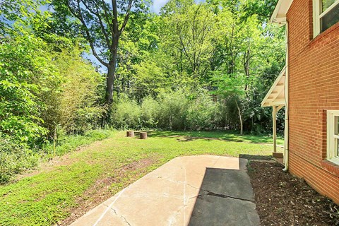 a pathway leading to a brick house with a yard and trees