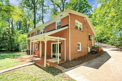 a small brick house with a porch and a driveway