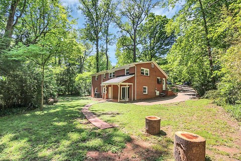 a brick house in the middle of a field with trees