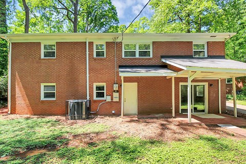 a brick house with a porch and a trash can