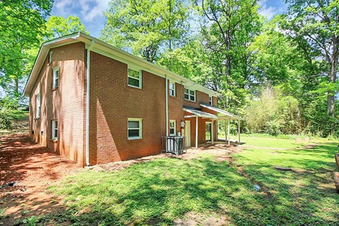 a brick house with green grass and trees