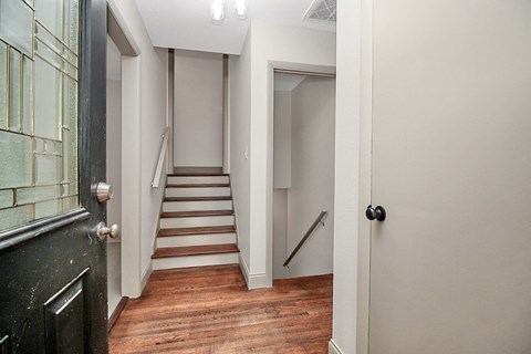 the hallway of a home with stairs and a door to a closet