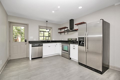 a large kitchen with stainless steel appliances and white cabinets