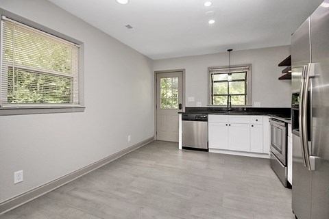 an empty kitchen with stainless steel appliances and a large window