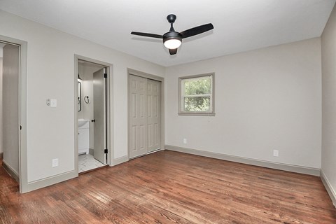 an empty living room with a ceiling fan and a door to a bathroom