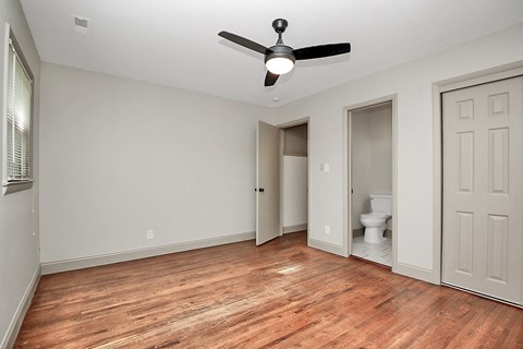 an empty living room with a ceiling fan and a door to a bathroom
