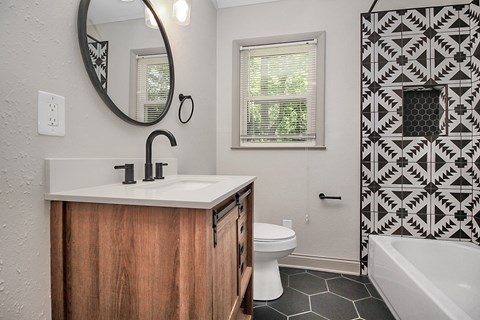 a bathroom with black and white tiles and a sink and a toilet