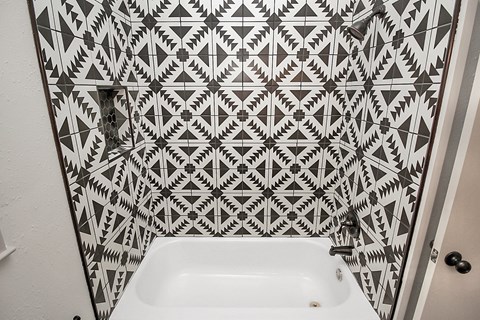 a small bathroom with a sink and a shower with geometric wallpaper