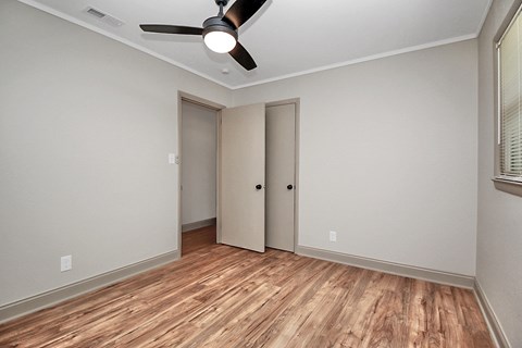 an empty living room with wood flooring and a ceiling fan