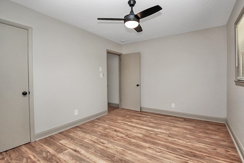 an empty living room with a ceiling fan and a door to a closet