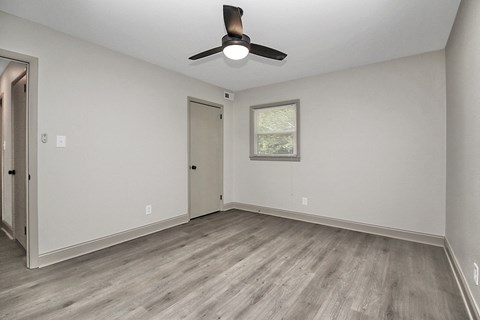 the spacious living room of an empty home with a ceiling fan