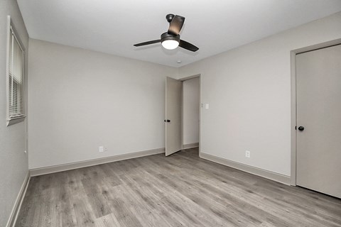 an empty living room with white walls and a ceiling fan