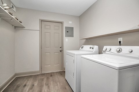 an empty laundry room with two white appliances and a white door