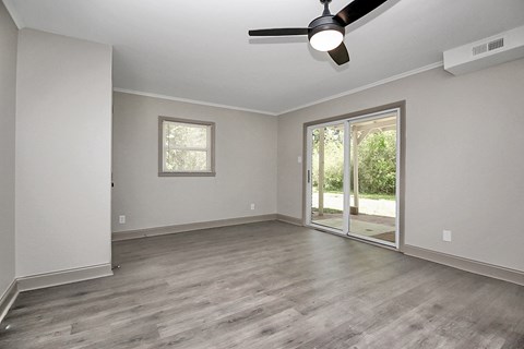 an empty living room with a sliding glass door to a patio