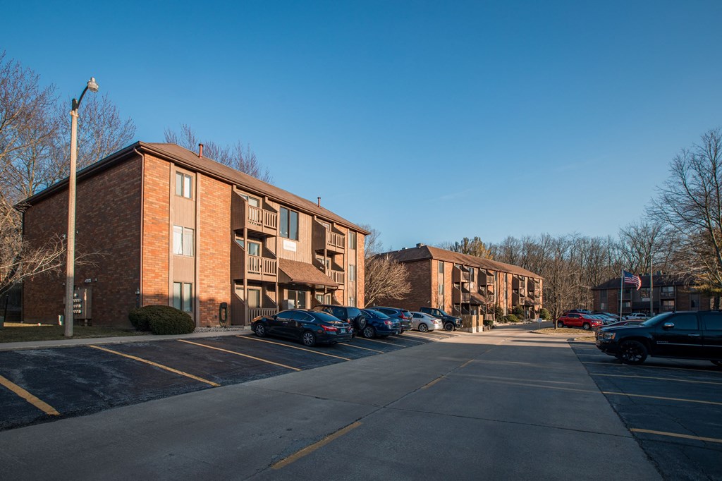 A parking lot in front of a brick apartment building.