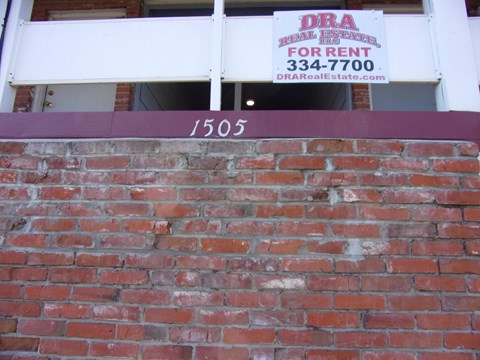 a brick wall in front of a building with a sign on it