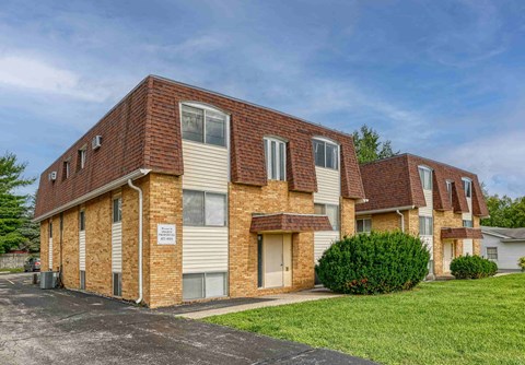 A building with a brown brick facade and a sign in front.