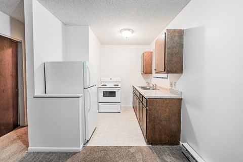 A kitchen with white appliances and wooden cabinets.