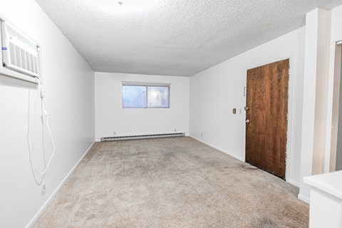 A room with a carpeted floor, a window, and a door.