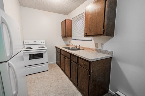 A kitchen with a white stove and wooden cabinets.