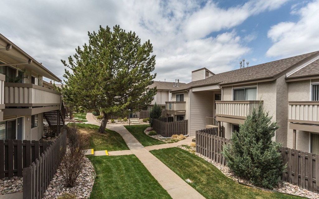 the view of an apartment building with a yard and sidewalk