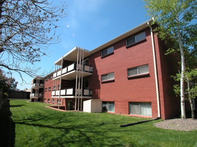 a red brick apartment building with a green lawn