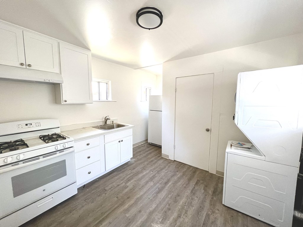 an empty kitchen with white appliances and white cabinets