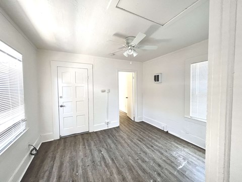 an empty living room with white walls and a ceiling fan