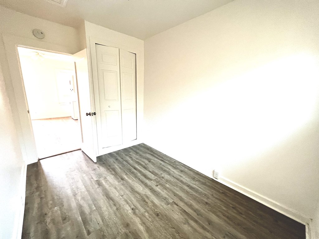 an empty room with white walls and wood floors
