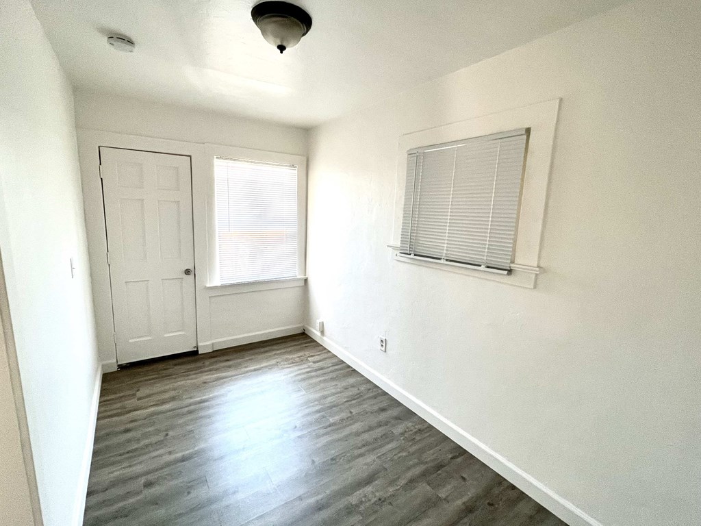 an empty living room with white walls and a white door and window