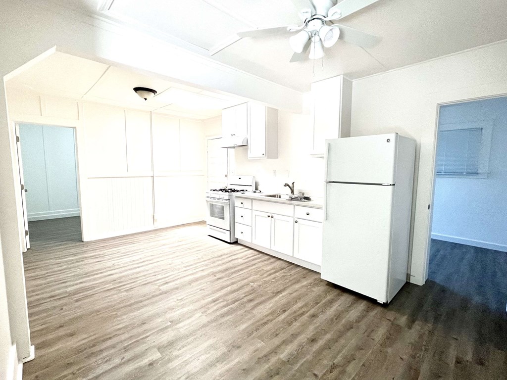 an empty kitchen with white cabinets and a refrigerator