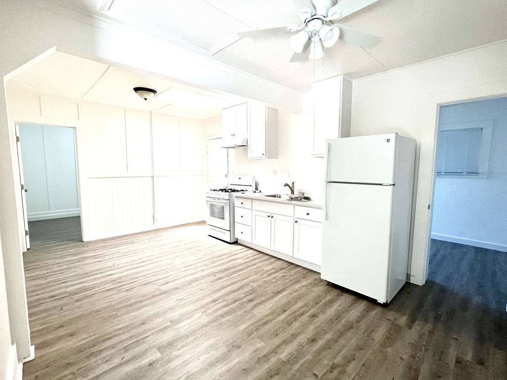 an empty kitchen with white cabinets and a refrigerator