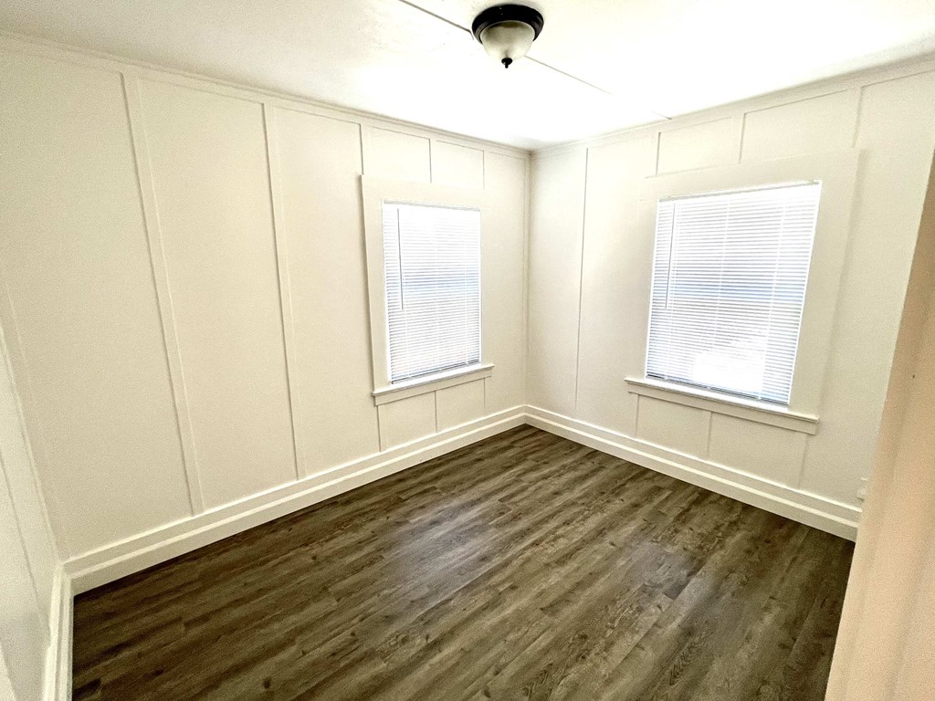 a room with wooden floors and white walls and windows