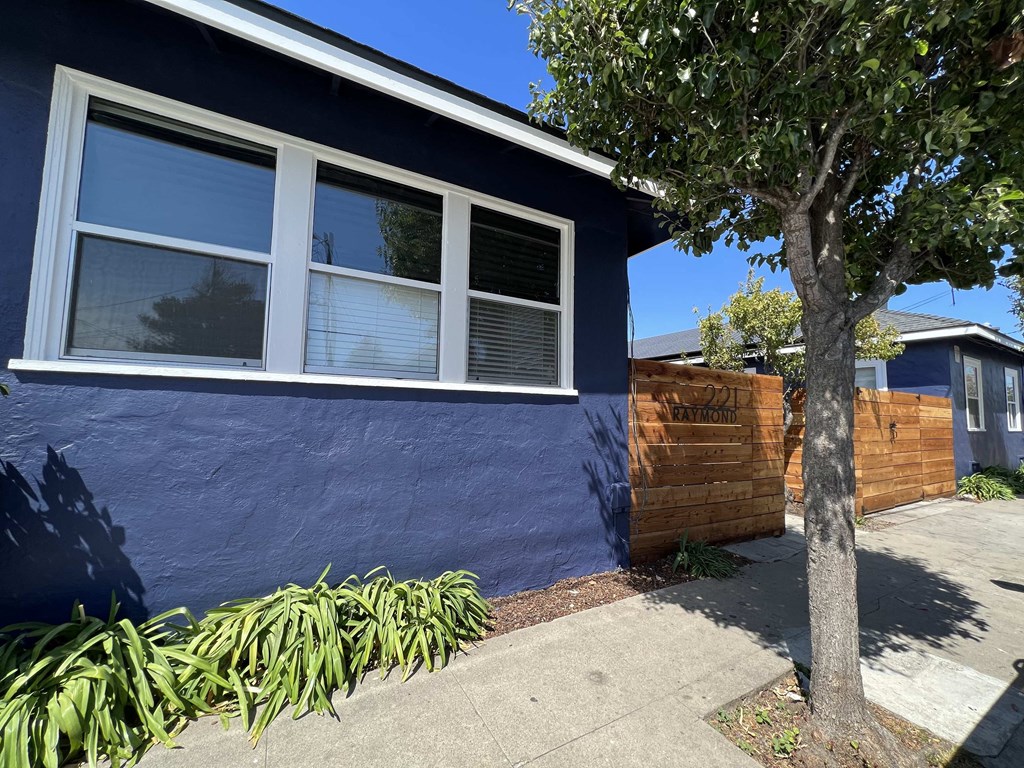 a blue house with a tree and a wooden fence