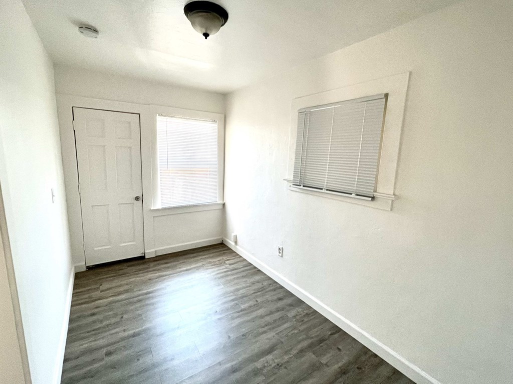 an empty living room with white walls and a white door and window
