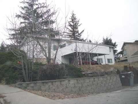 A house with a white exterior and a stone wall in front.