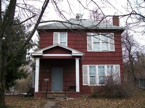 A red house with white trim and a grey door.