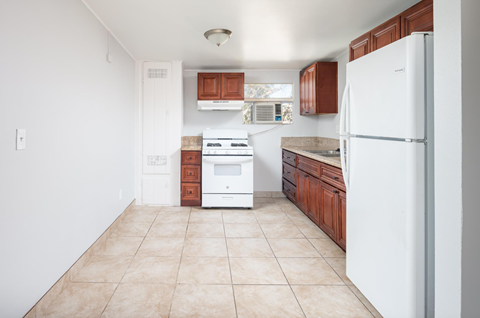 A kitchen with white appliances and brown cabinets.