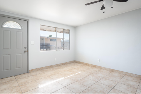 Empty room with tiled floor and sliding glass door.