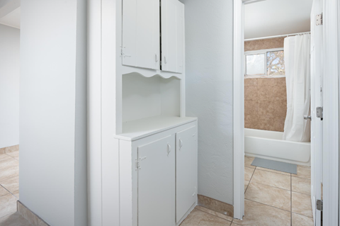 A white bathroom with a shower and a cabinet.