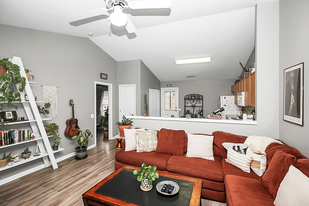 a living room with a red couch and a ceiling fan