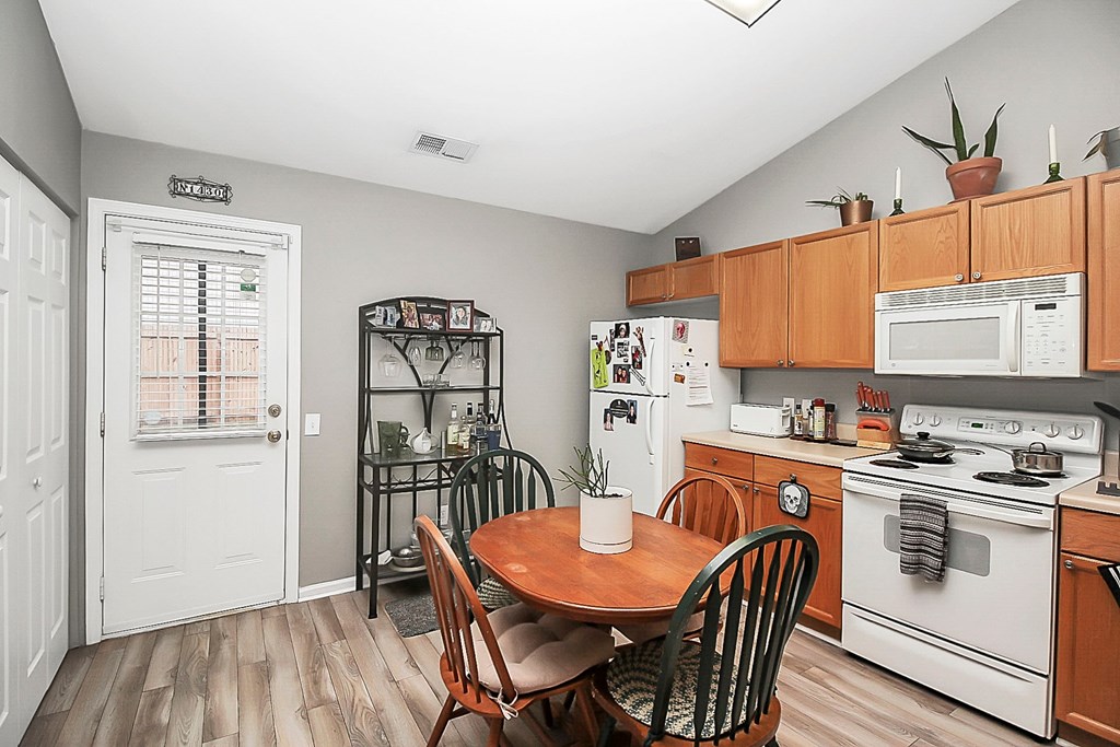 a kitchen with white appliances and a table and chairs