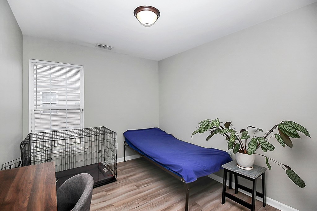 a room with a bed and a table and a bird cage