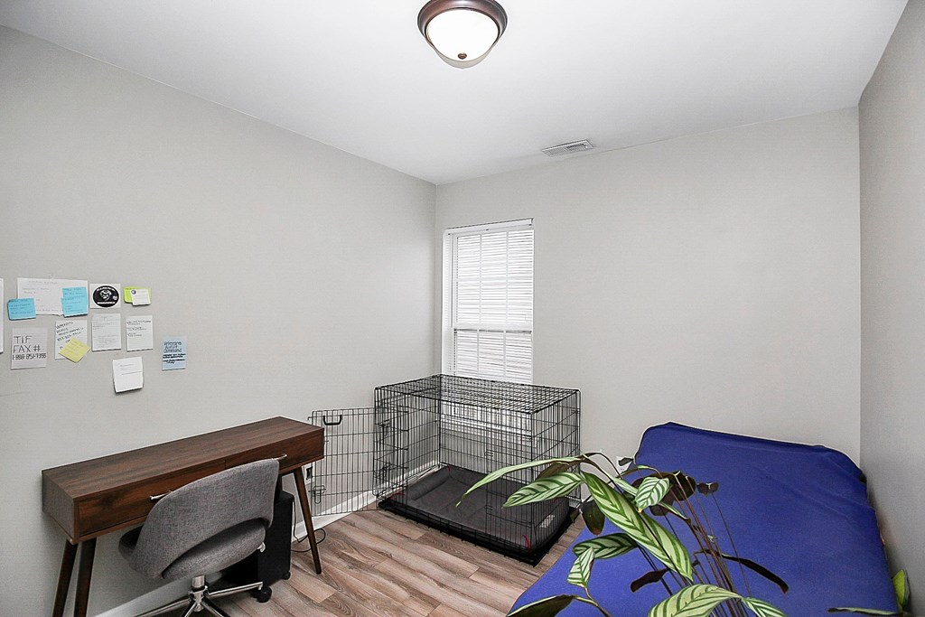 a bedroom with a bed and a desk and a cage