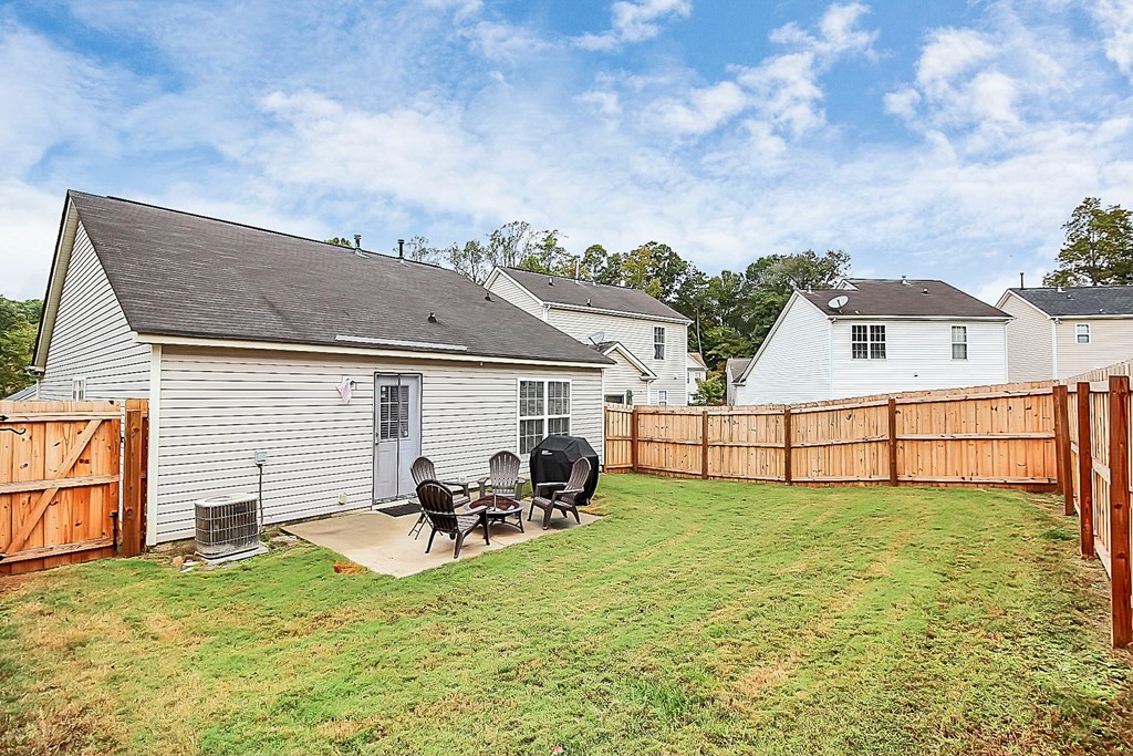 a backyard patio with a table and chairs and a fence