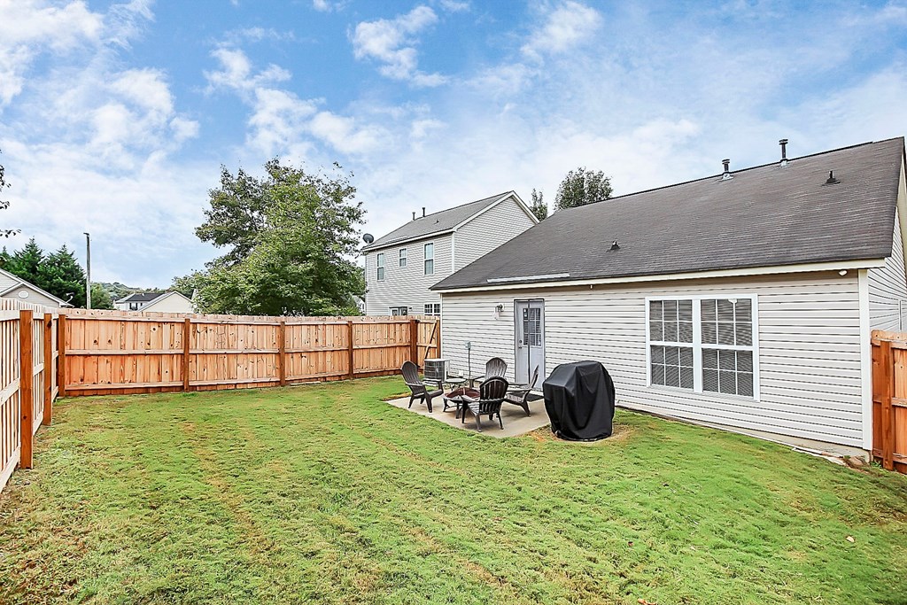 a backyard with a fence and a yard with a table and chairs